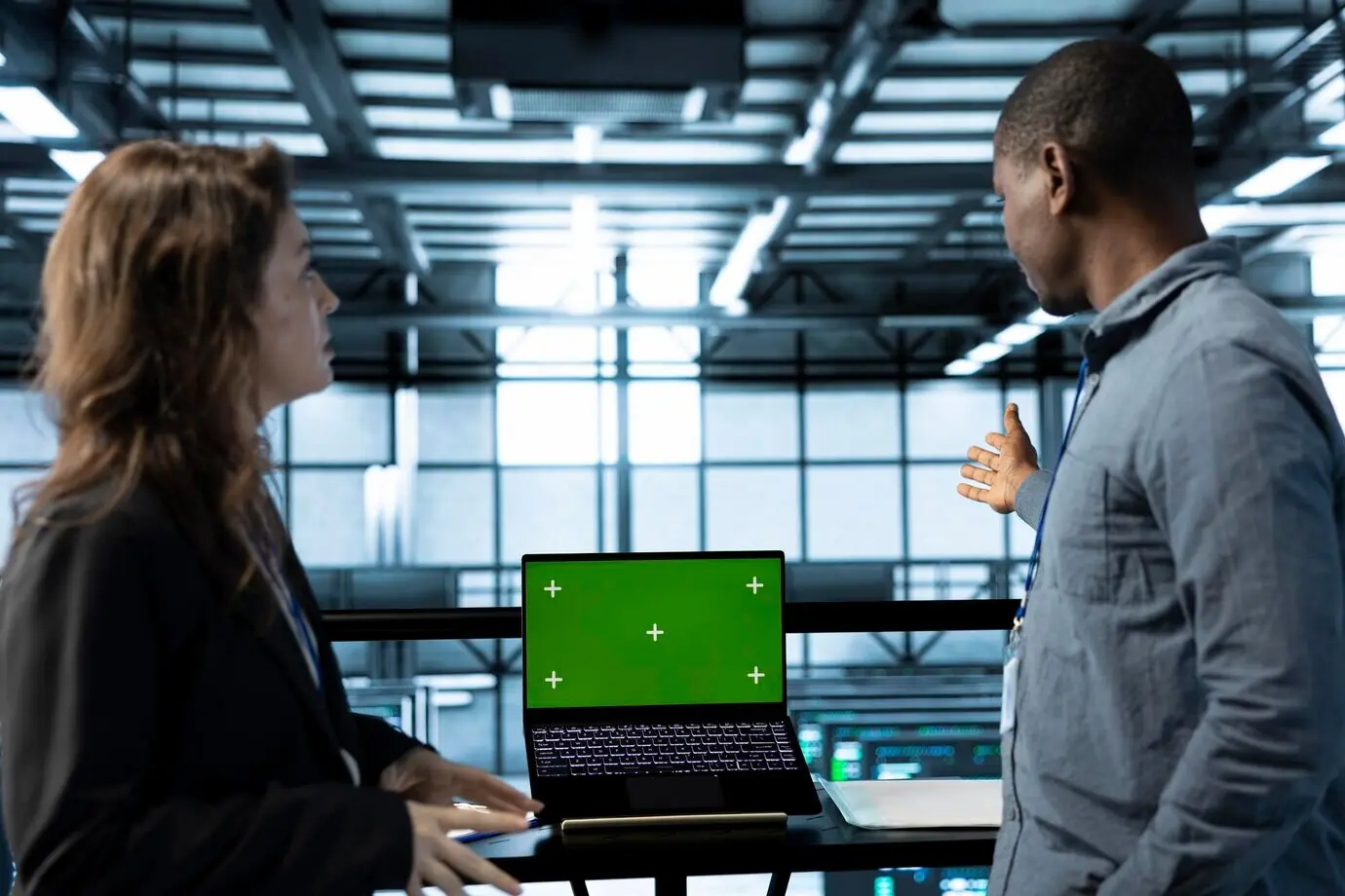 Team von Ingenieuren einer Serverfarm, das einen isolierten Bildschirm-Mockup-Laptop nutzt.